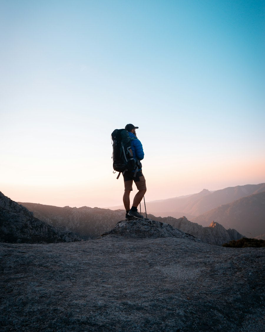 Hiker with a large backpack on a rocky ridge at sunset
